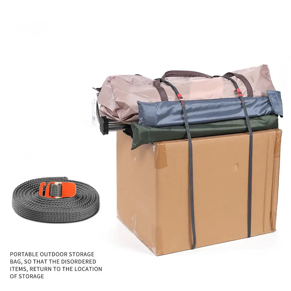 Cardboard storage box with fabric bags strapped on top and a coiled strap beside it.