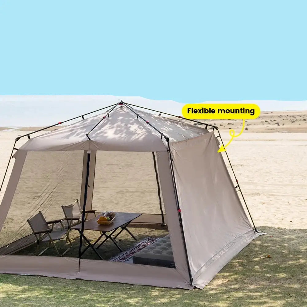 Portable screened canopy tent set up on sandy ground with camping furniture inside.