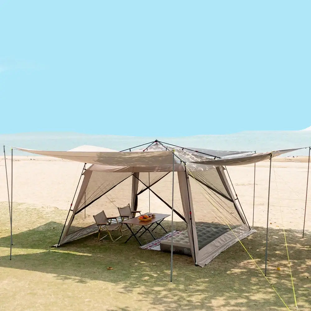 Canopy tent set up on a beach with camping furniture inside.