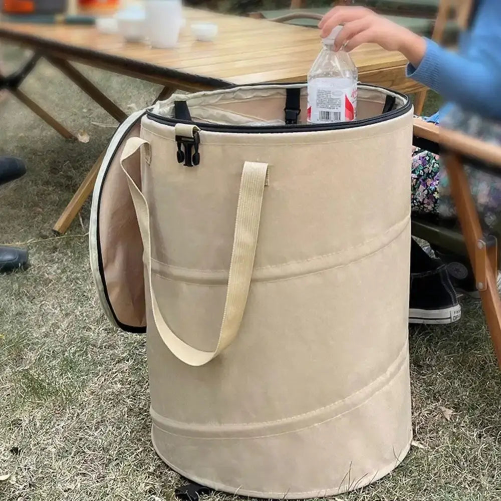 Cylindrical beige fabric container with handles and a zippered top.