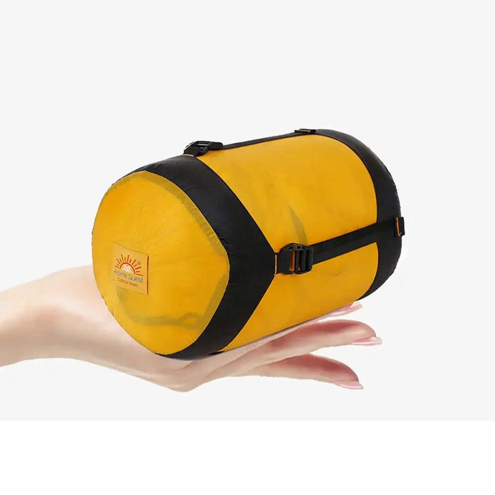 Yellow cylindrical sleeping bag or camping roll with black straps, resting on an open palm.