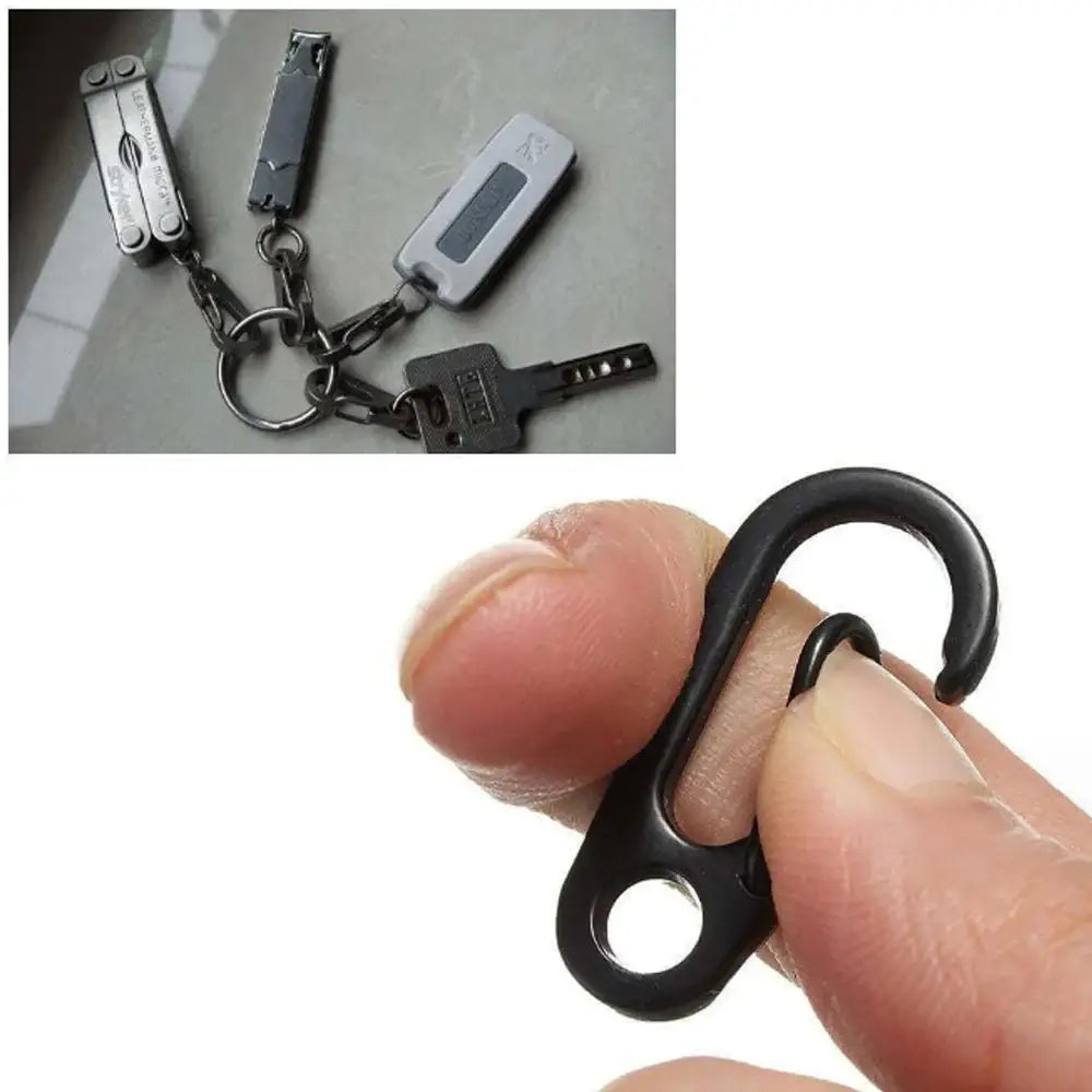 Small black metal hook or carabiner held between a thumb and forefinger.