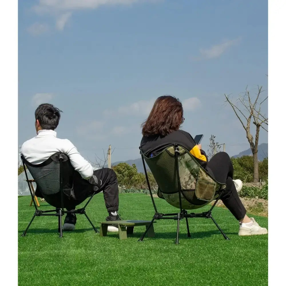 Two people sitting in outdoor chairs on a grassy area.