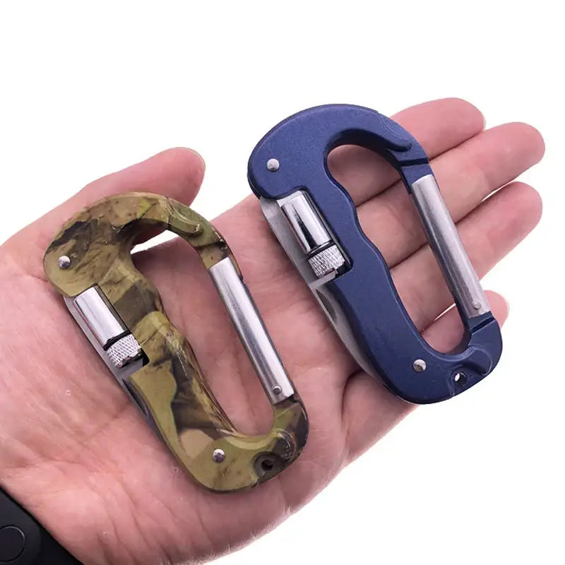 Carabiners in camouflage and blue colors resting on an open palm.