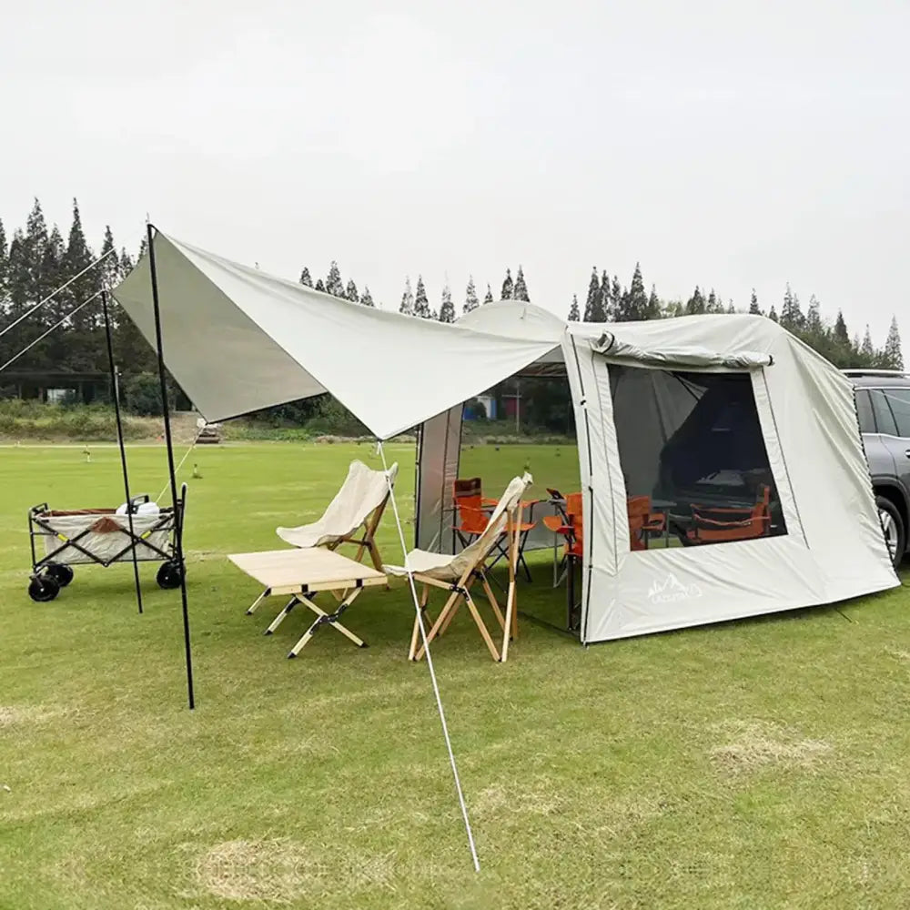 Camping setup with a tent, canopy, and folding chairs on a grassy area.