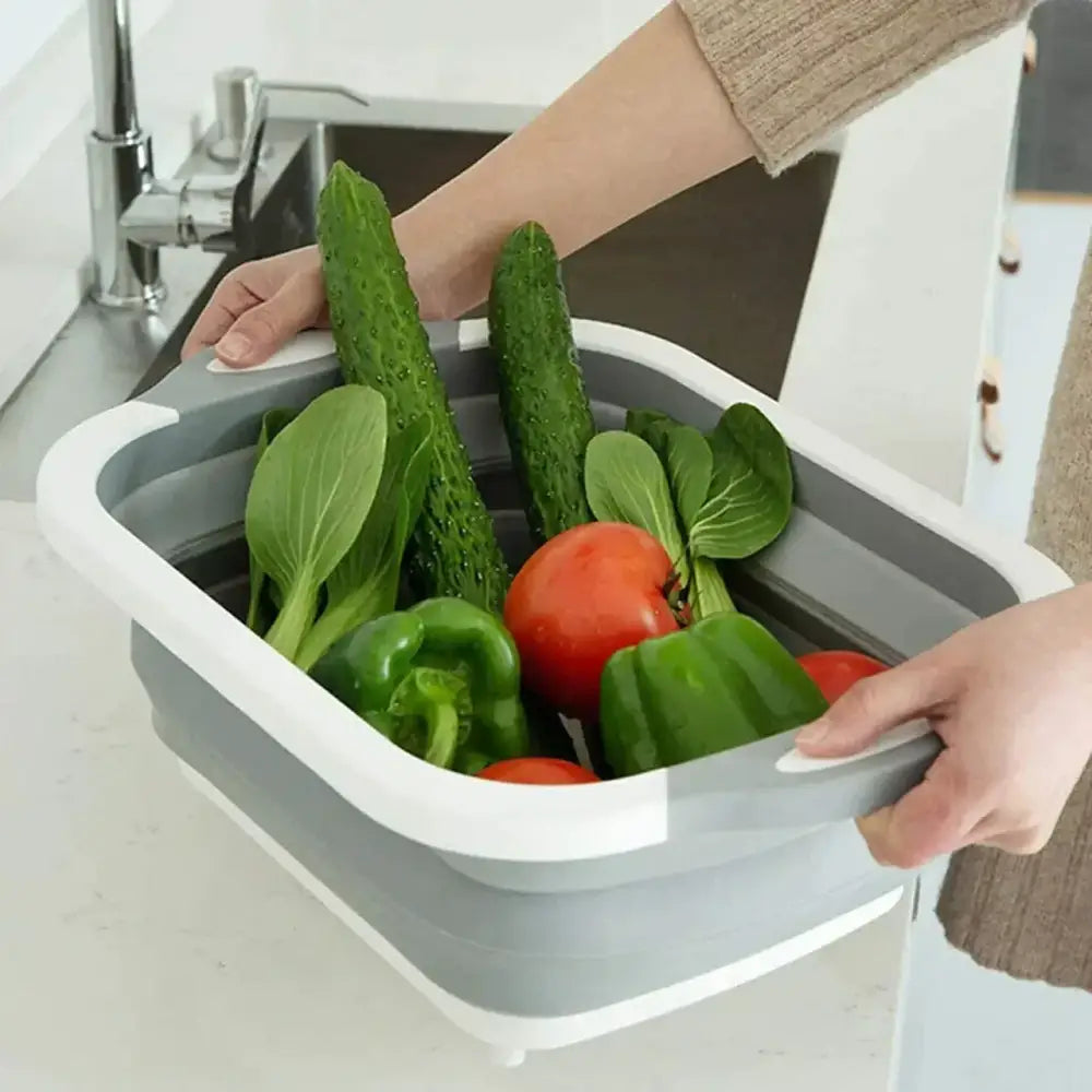 Collapsible sink basin filled with fresh vegetables being washed.