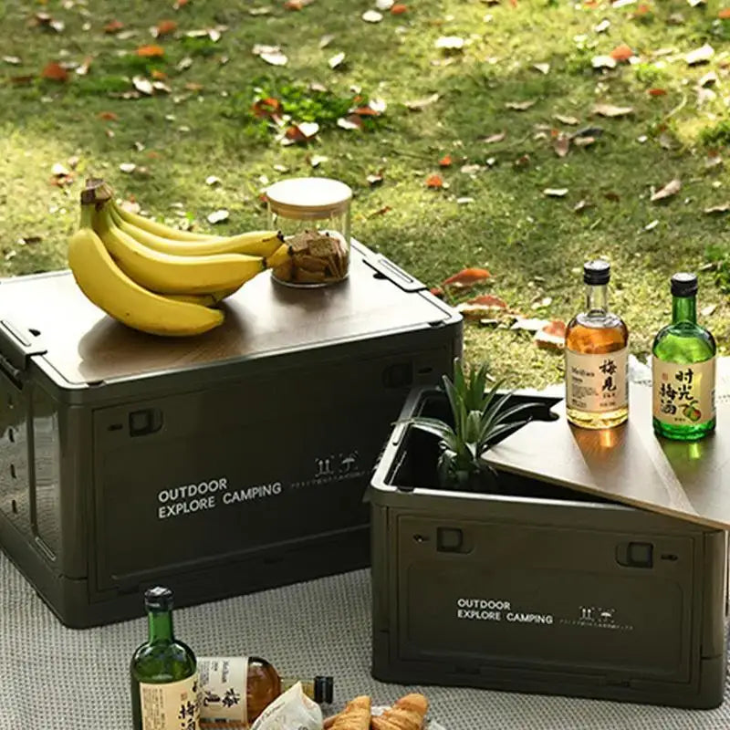 Camping storage boxes with food and drinks on top.