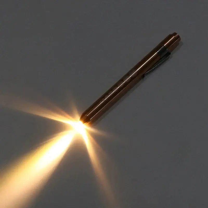 Metallic pen-shaped object emitting a bright, star-like beam of light.