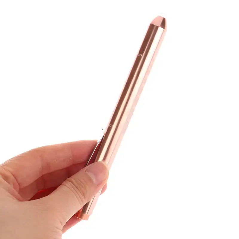 Rose gold metallic stylus or digital pen held between fingers.