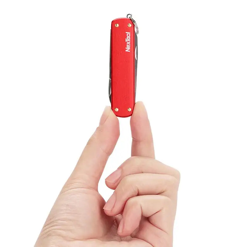 Red Swiss Army knife held between two fingers.