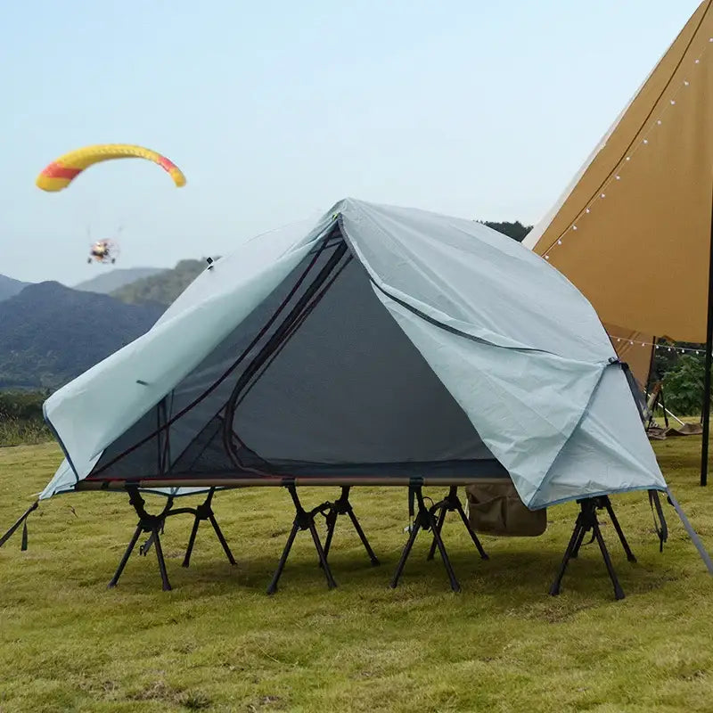 Tent elevated on metal legs or supports in a camping setting.