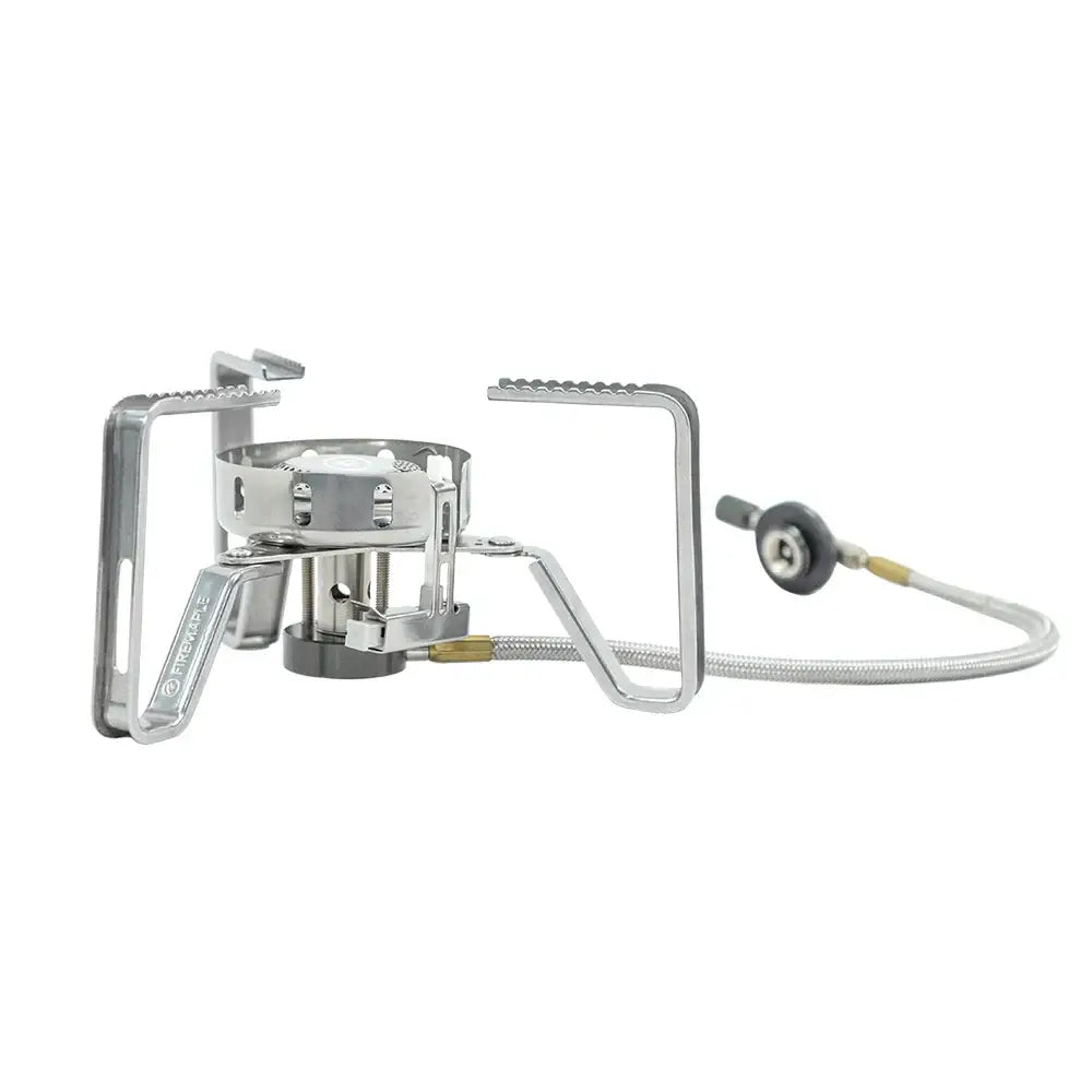 Portable camping stove with folding legs and a fuel hose attachment.