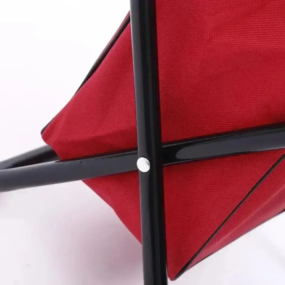 Red fabric stretched over a black frame, forming part of a folding chair or seat.