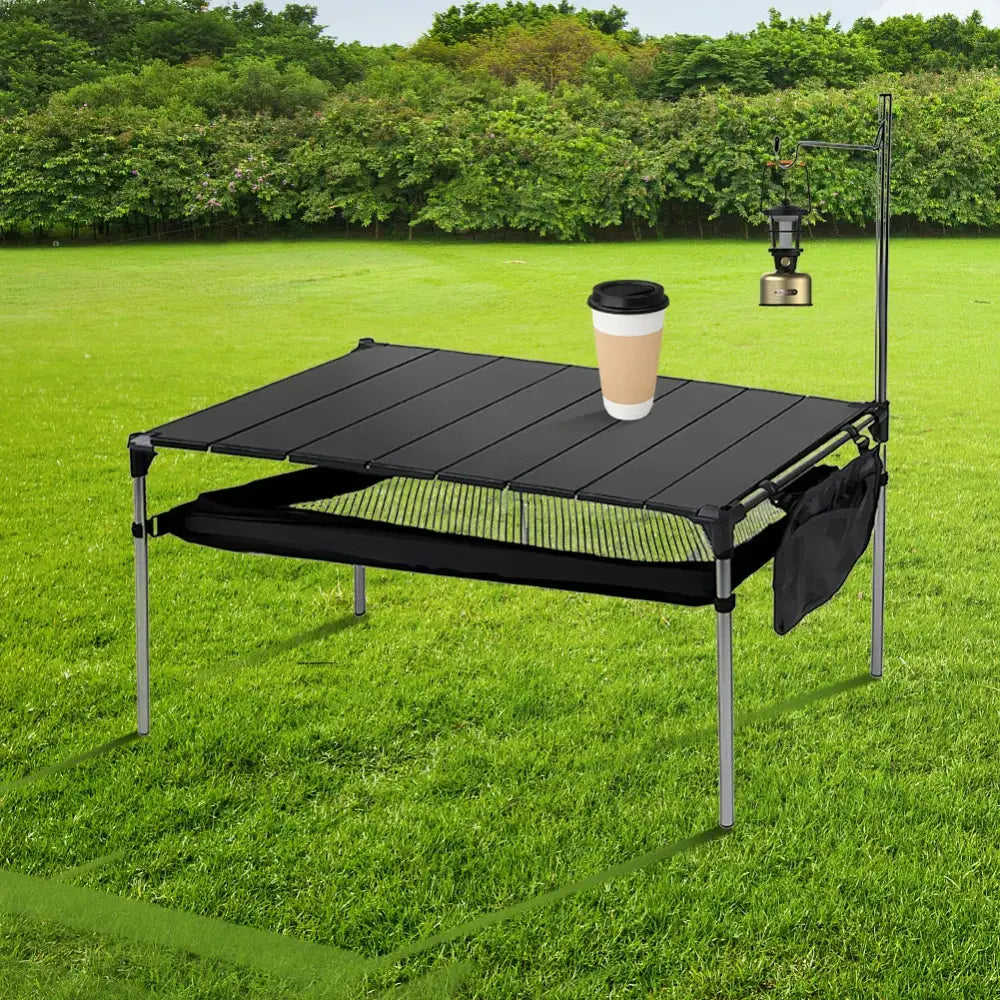 Portable folding table with a black top and metal legs set up on grass.