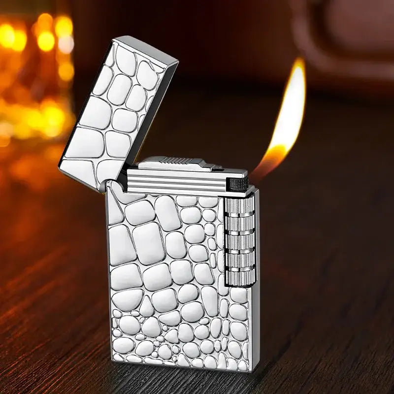 Silver cigarette lighter with a crocodile skin pattern engraved on its surface.