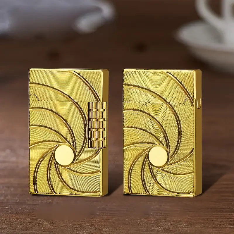 Two gold-colored lighters with engraved spiral designs on their surfaces.