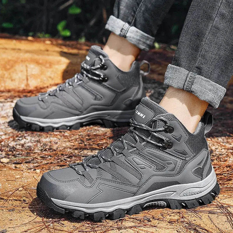 Pair of gray hiking boots with rugged soles worn on feet.