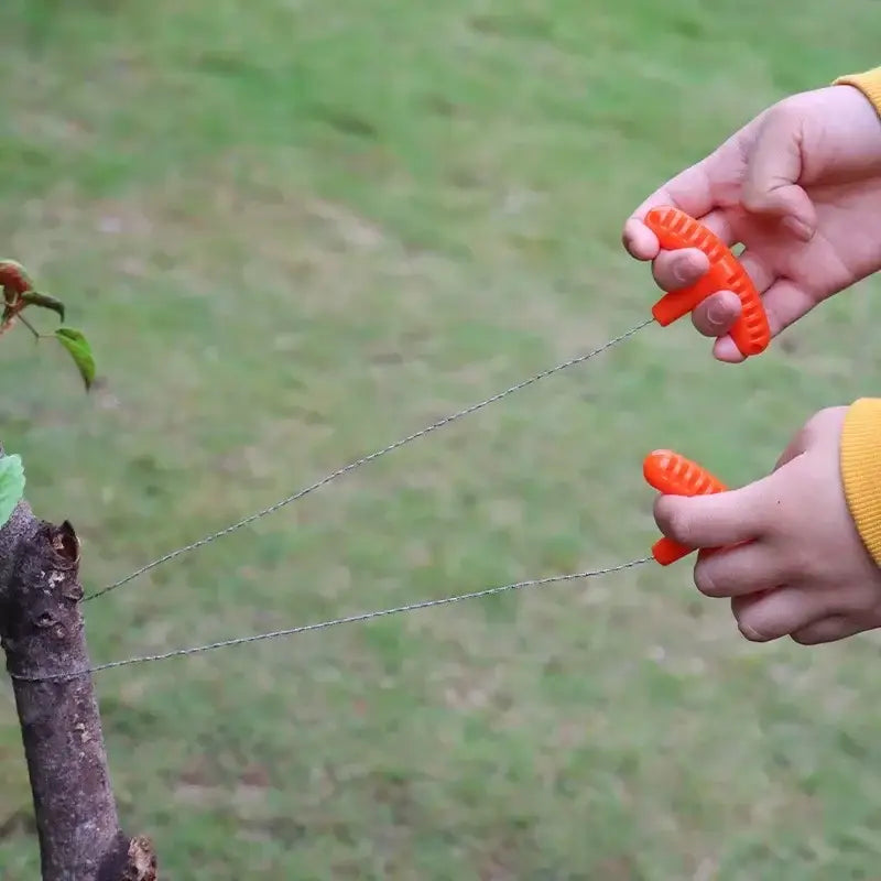 Hands holding a toy handsaw cutting a tree branch.