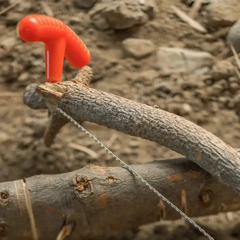 Makeshift seesaw created from a tree branch with a bright orange handle.