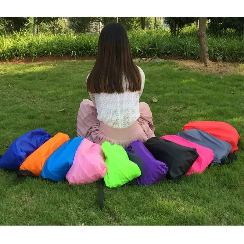 Person sitting on grass surrounded by colorful inflatable cushions or pillows.