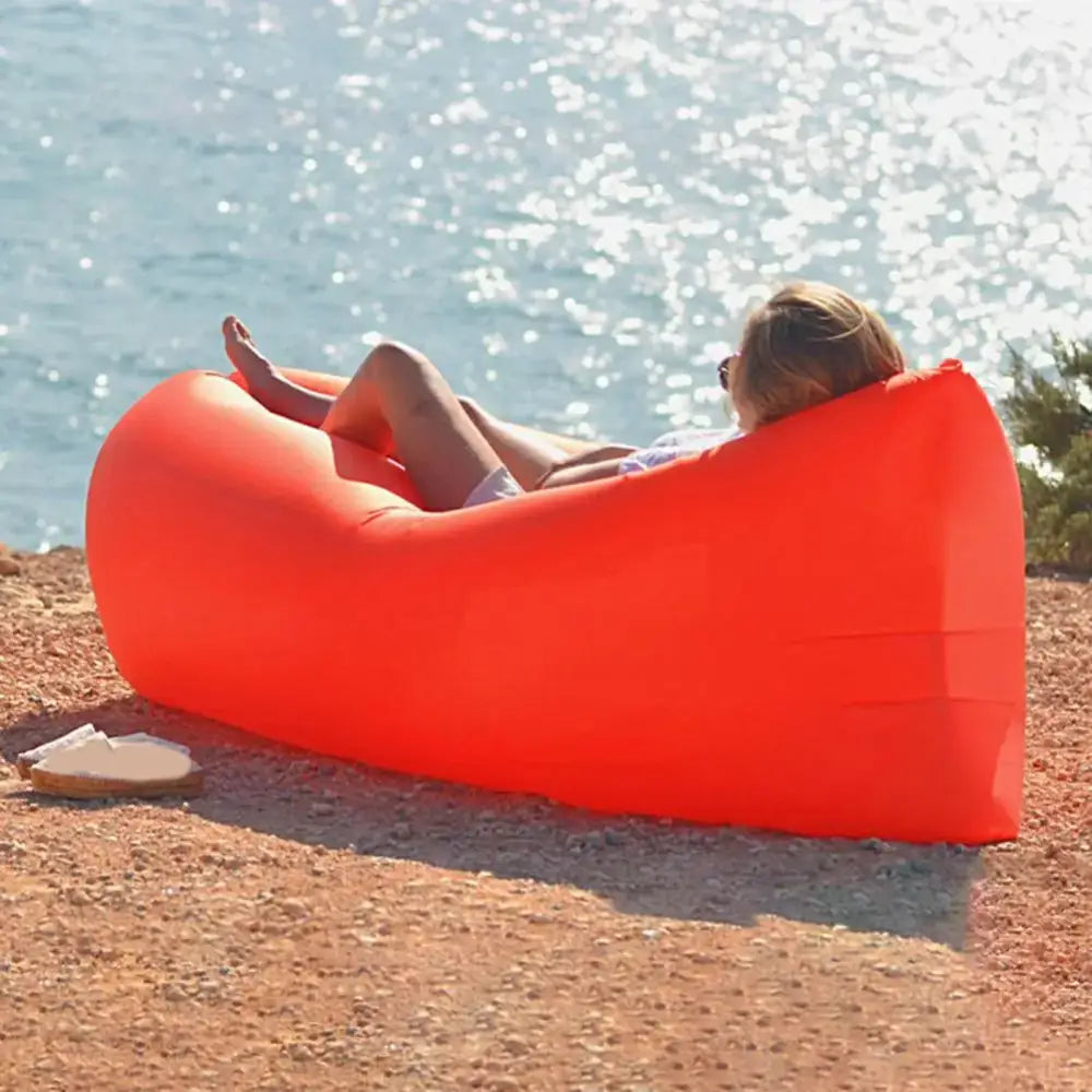 Bright orange inflatable lounger or air sofa on a beach.