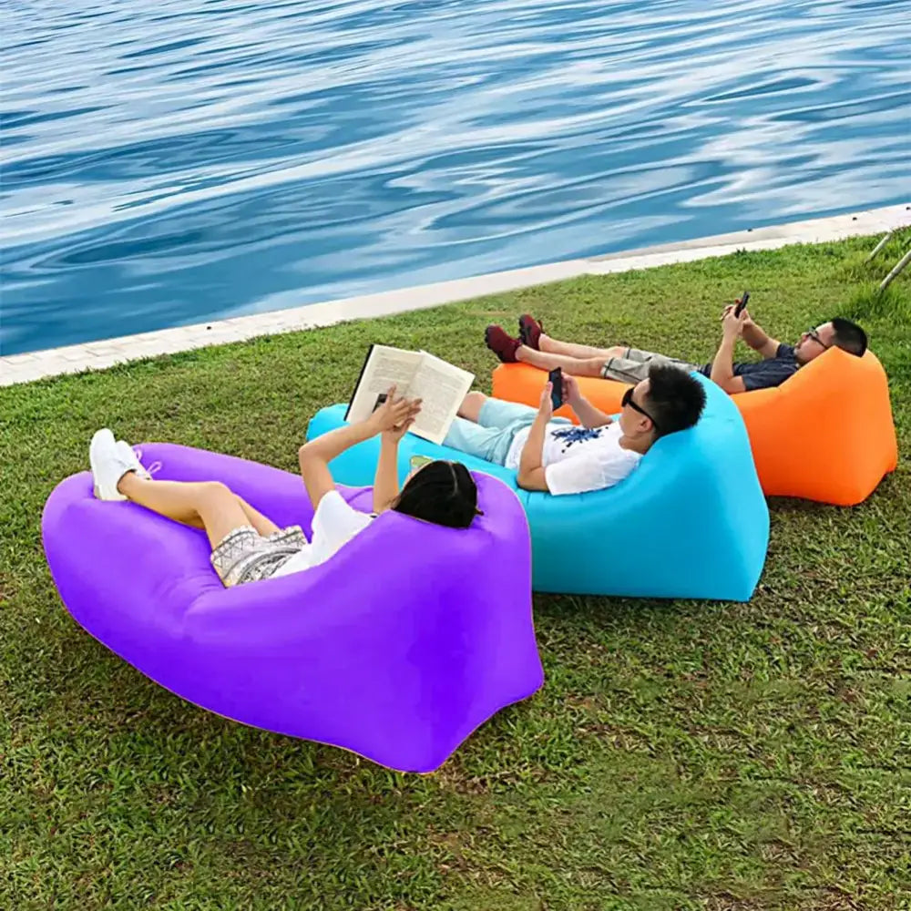 Inflatable loungers in vibrant colors positioned on grass near water.