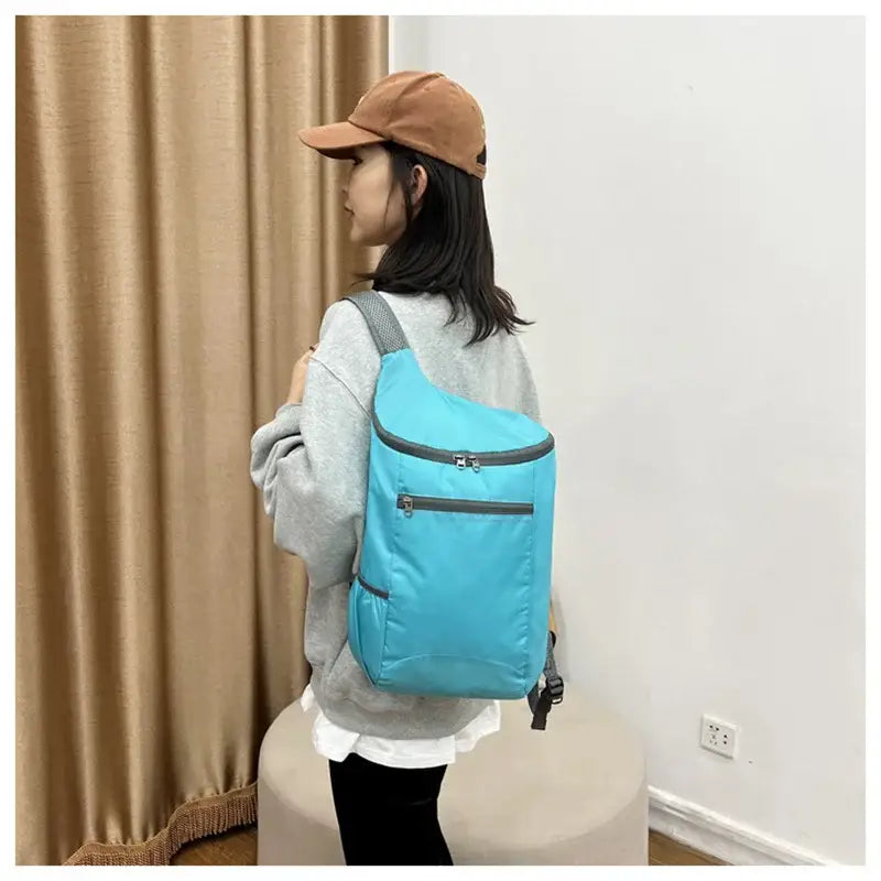 Bright blue backpack with multiple zippered compartments worn by a person.