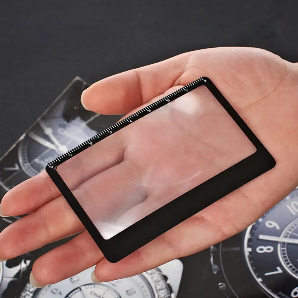 Rectangular magnifying lens with a black frame held in an open palm.