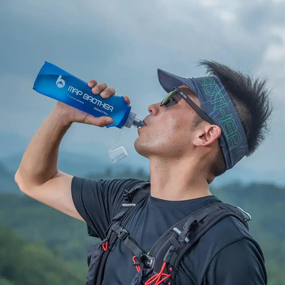 Blue water bottle being drunk from by a person wearing sunglasses and a visor.