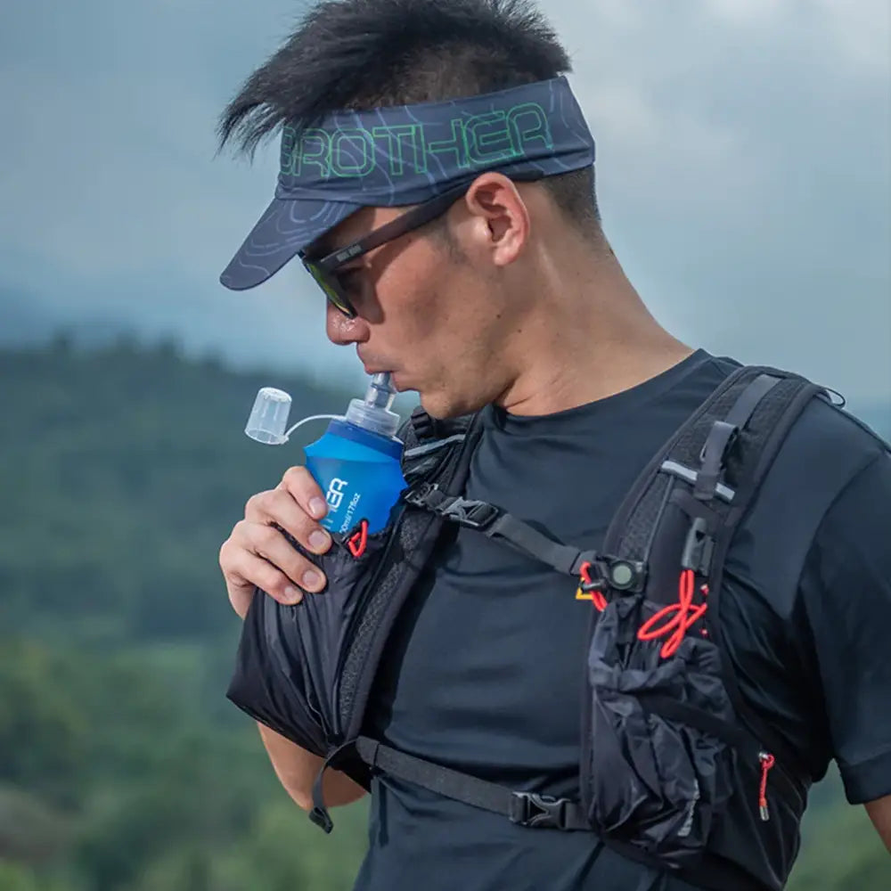 Person wearing a visor and sunglasses drinking from a blue water bottle.