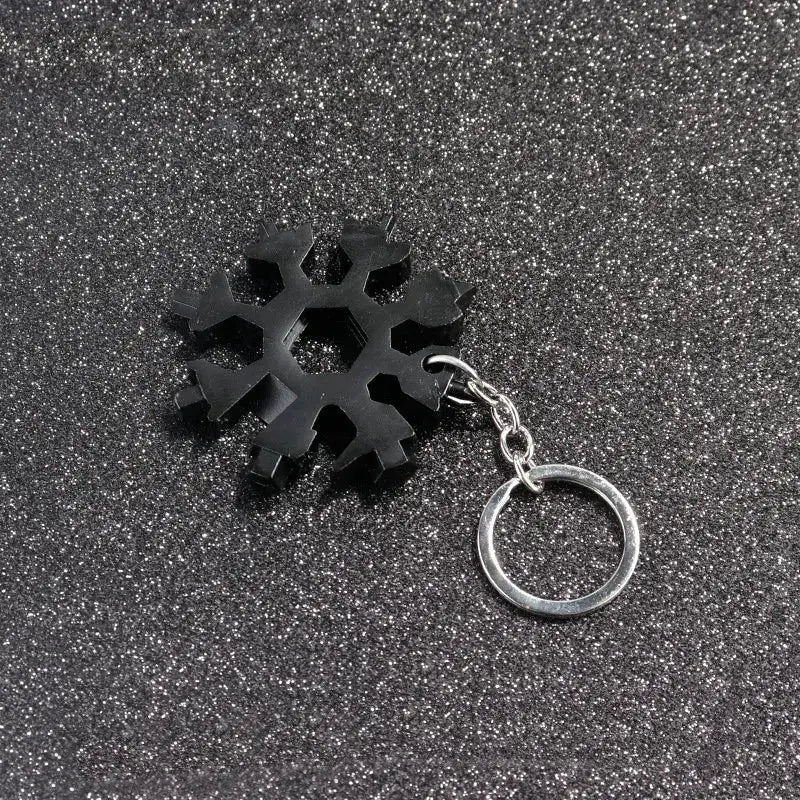 Black snowflake-shaped multitool keychain with various tool cutouts.