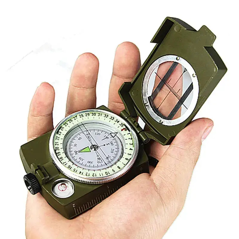 Military-style compass with a folding lid held in an open hand.