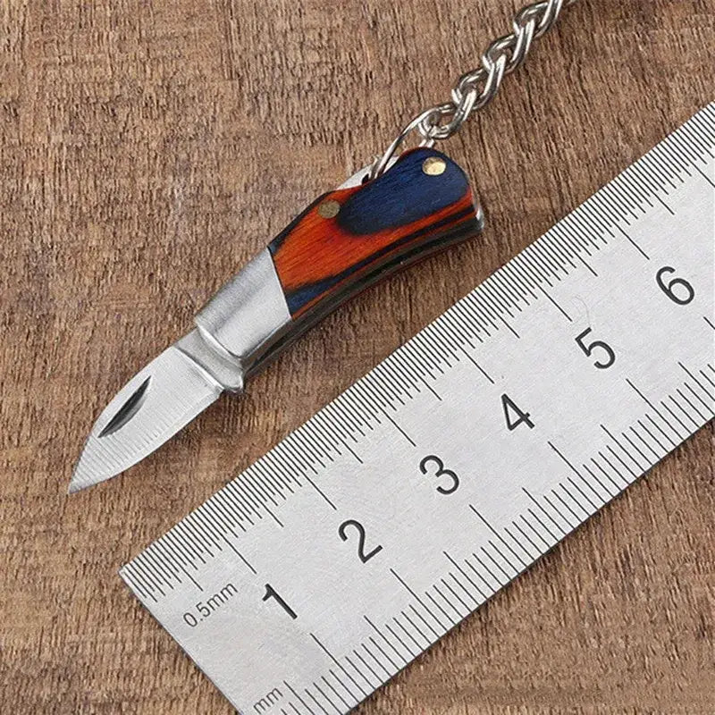 Miniature folding knife with a colorful wooden handle attached to a keychain.