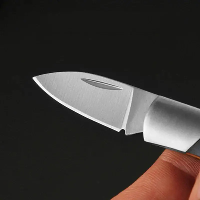 Sharp, metallic folding knife blade held by fingertips.