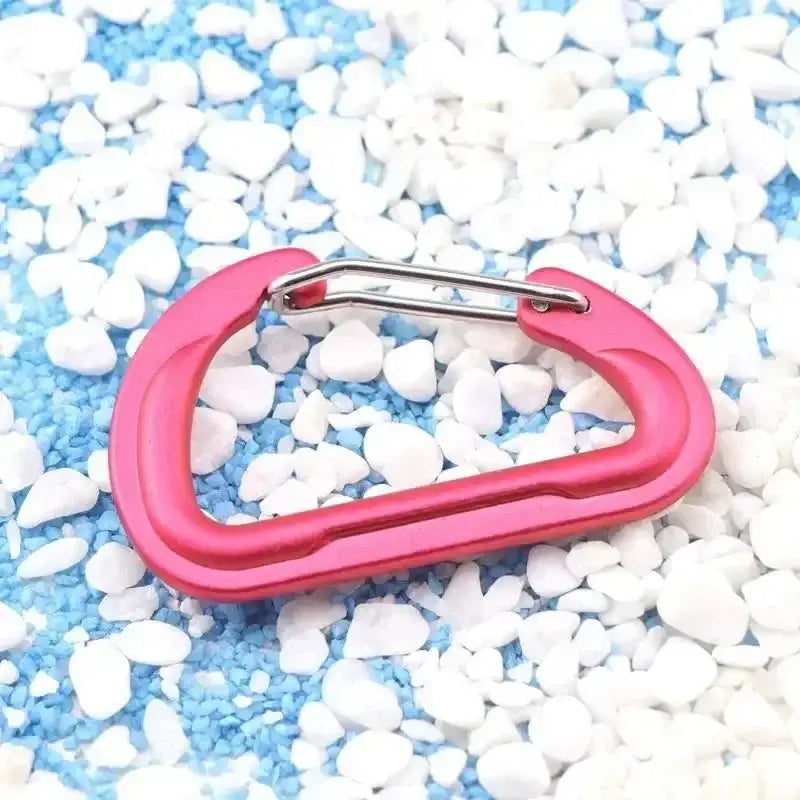 Pink carabiner clip against a background of small white pebbles.