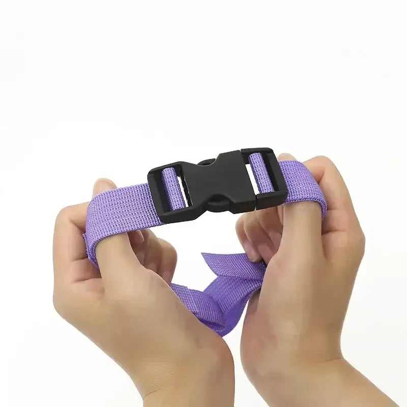 Purple fabric strap with a black plastic buckle being held by hands.