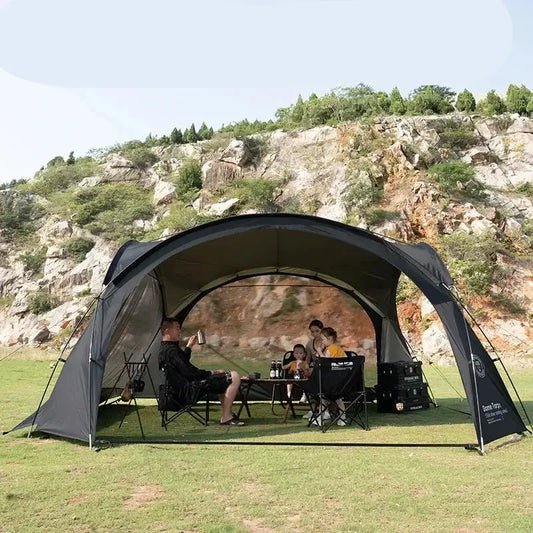 Canopy tent set up on grass with people sitting inside.