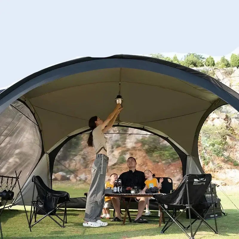 Canopy tent set up for outdoor camping with chairs and equipment inside.