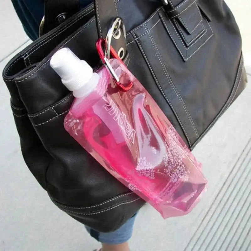 Collapsible pink water bottle attached to a black leather handbag.