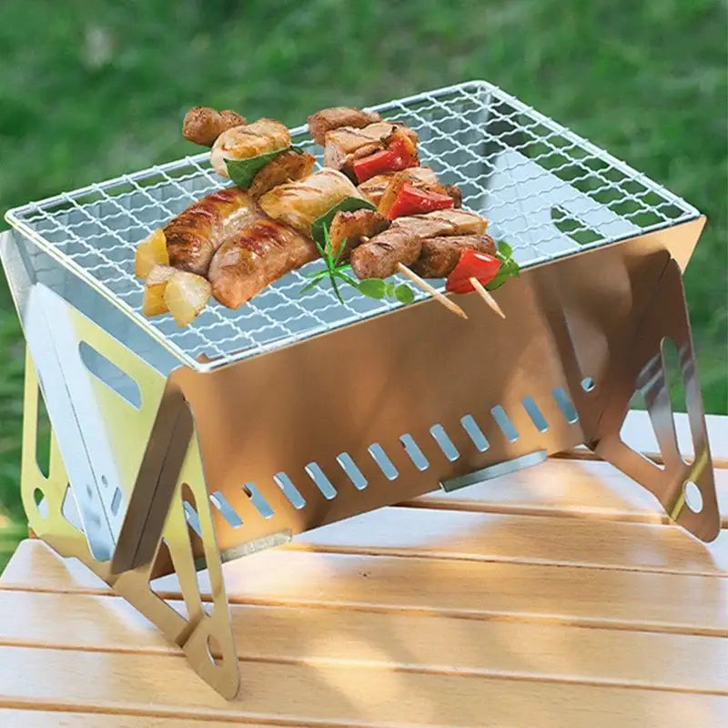 Portable folding barbecue grill with skewers of meat and vegetables cooking on top.