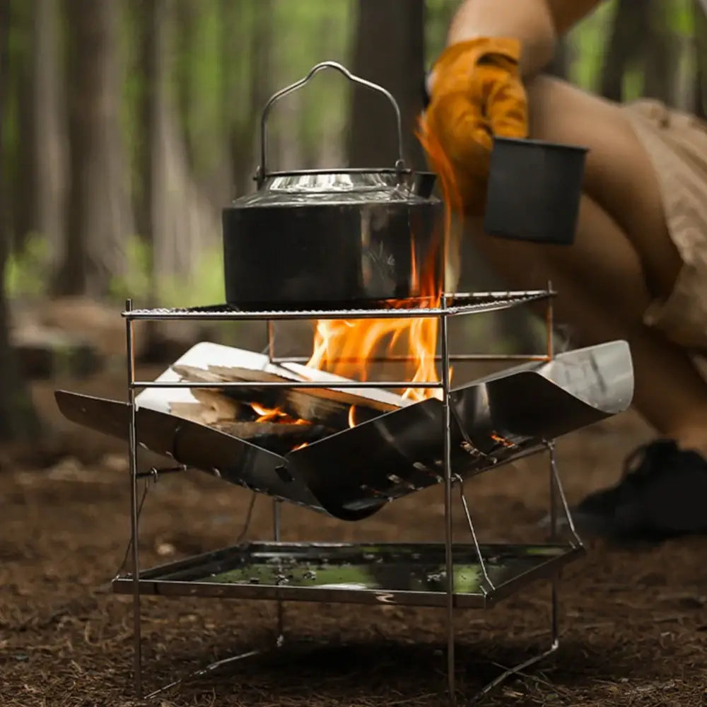 Portable camping stove with a fire burning inside and a kettle on top.