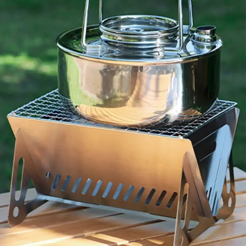 Portable camping stove with a shiny metal pot on top.