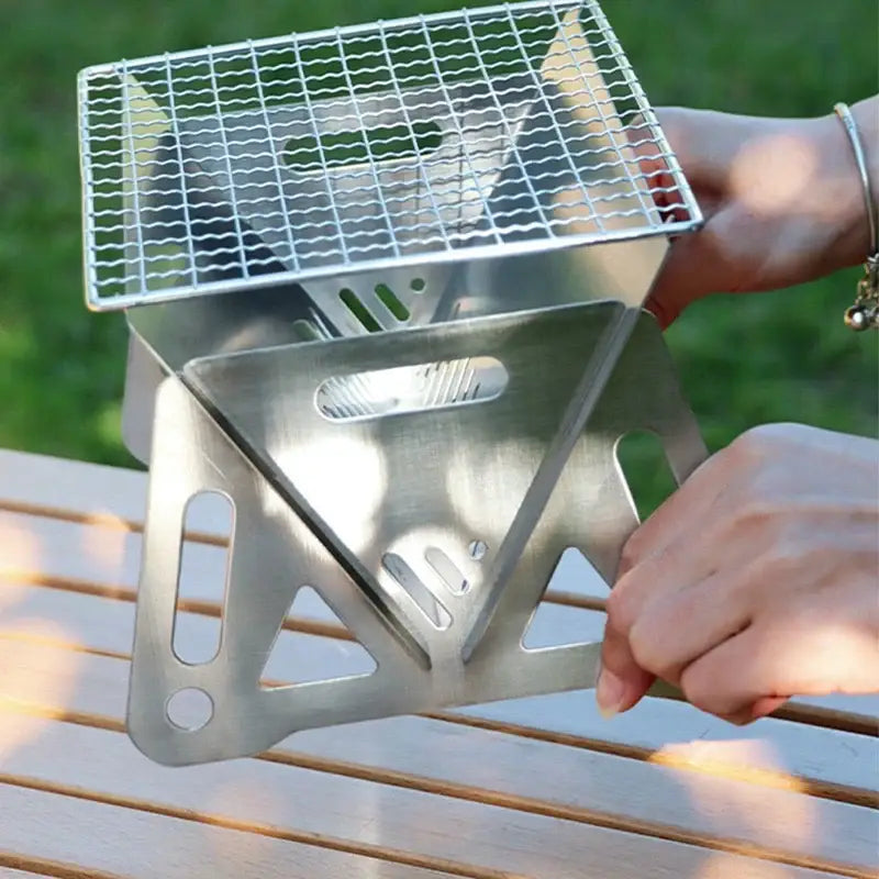 Triangular portable camping stove with a wire grill top.