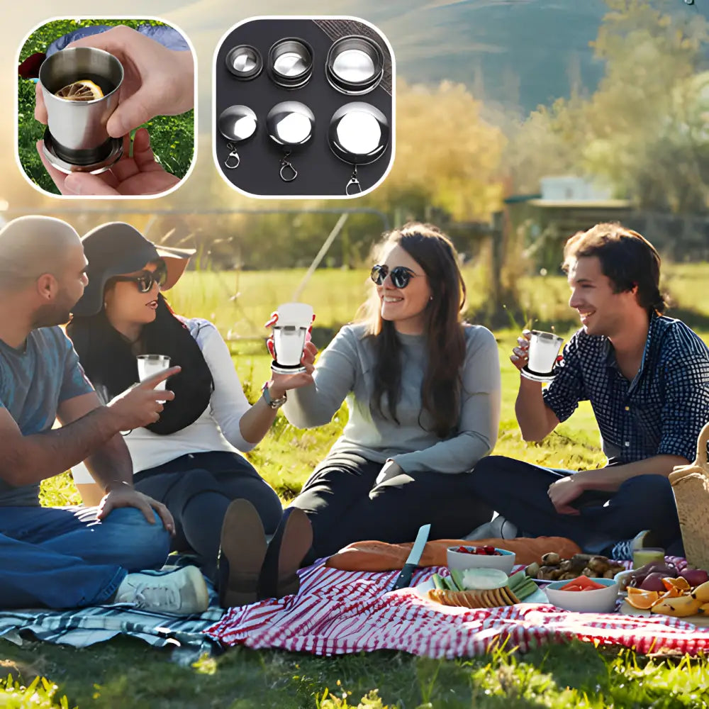 Group of friends enjoying a picnic outdoors on a blanket with food and drinks.