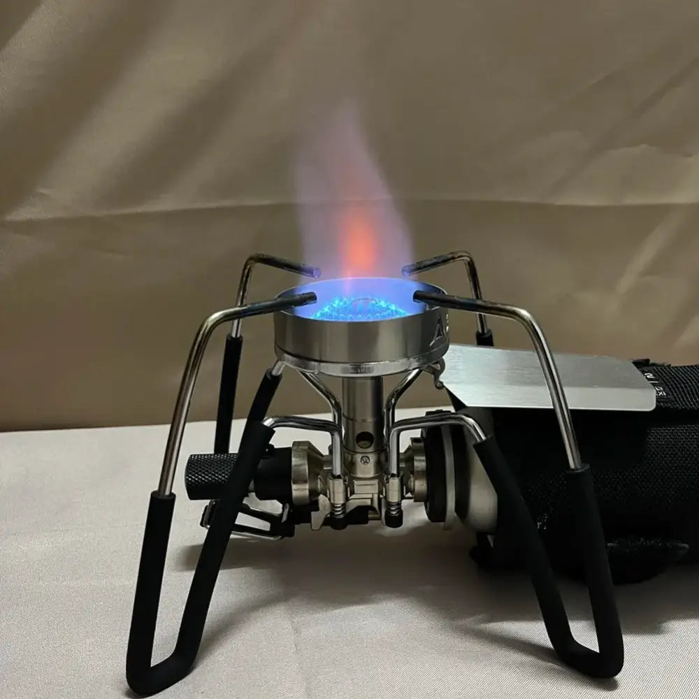 Portable camping stove with a blue flame burning on its burner.