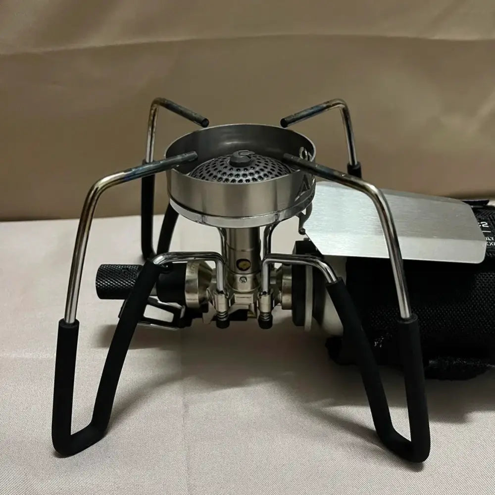 Portable camping stove with four folding legs and a circular burner.