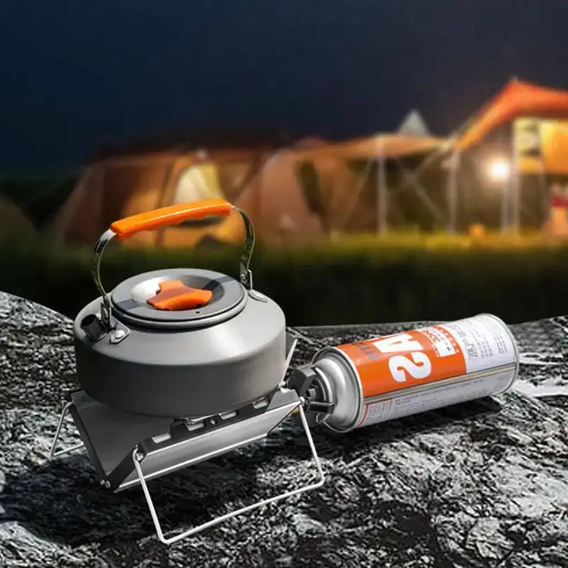 Camping stove with a kettle and gas canister on a rocky surface.