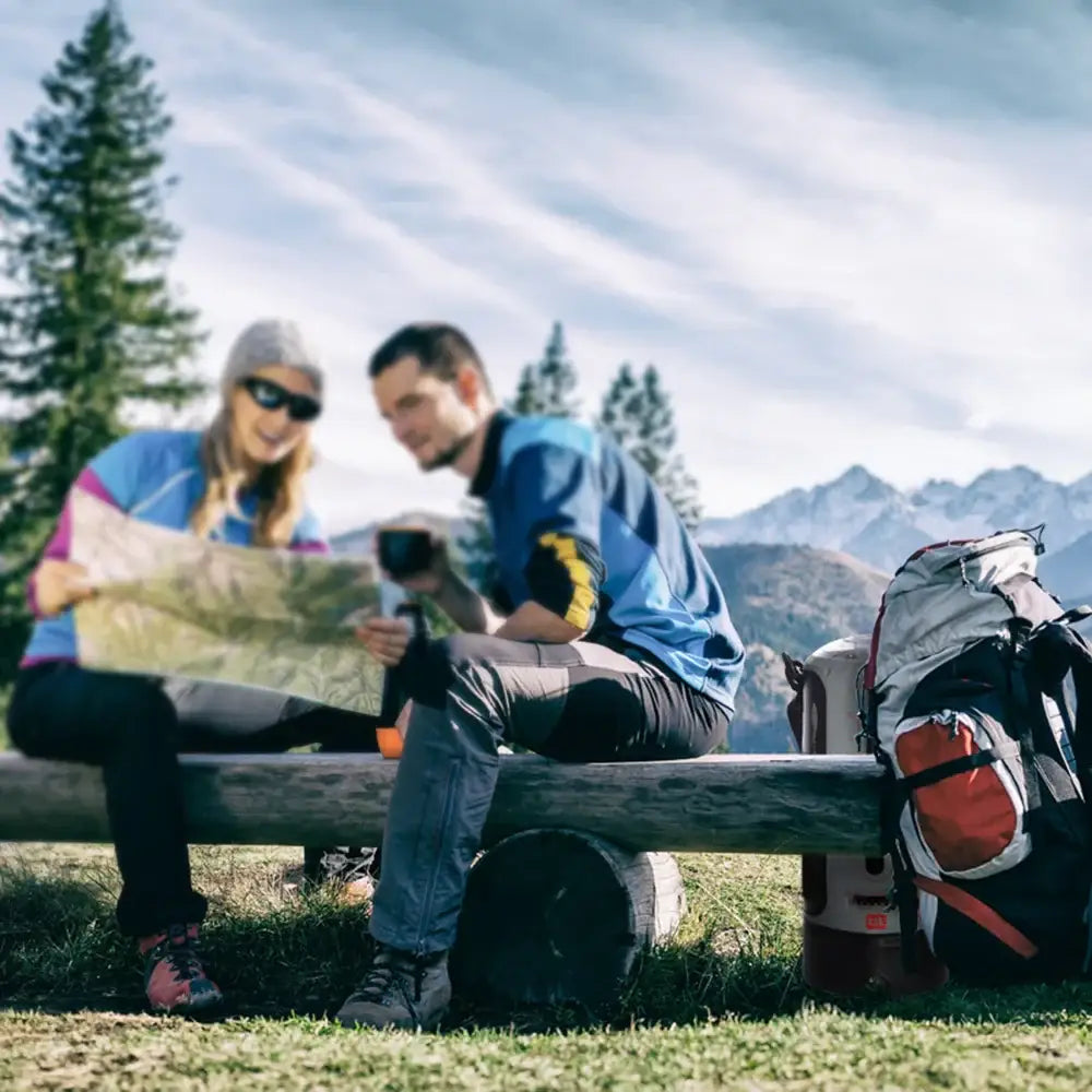 Two hikers sitting on a bench consulting a map.