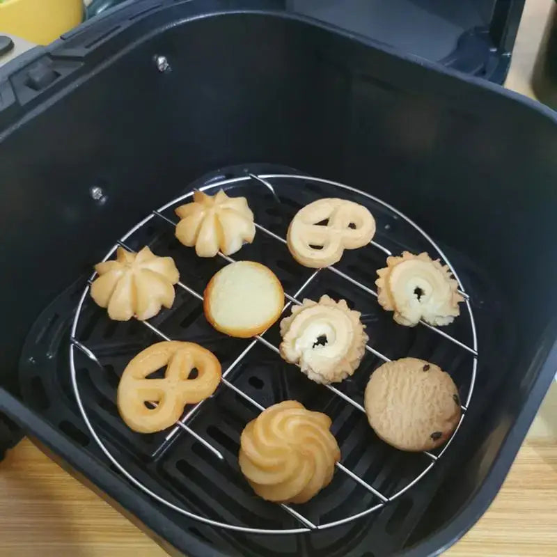 Air fryer basket containing various cookies and pastries on a wire rack.