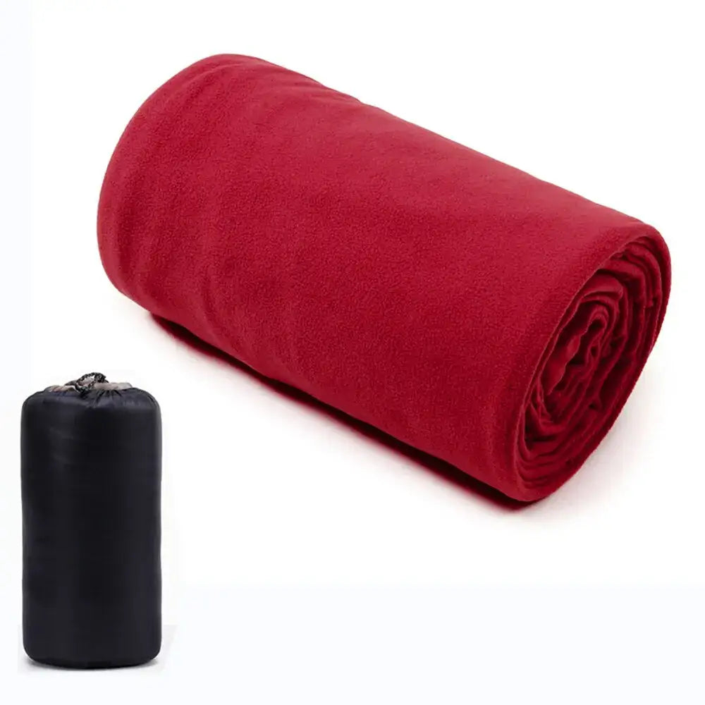 Red rolled-up fleece blanket with a black storage bag beside it.